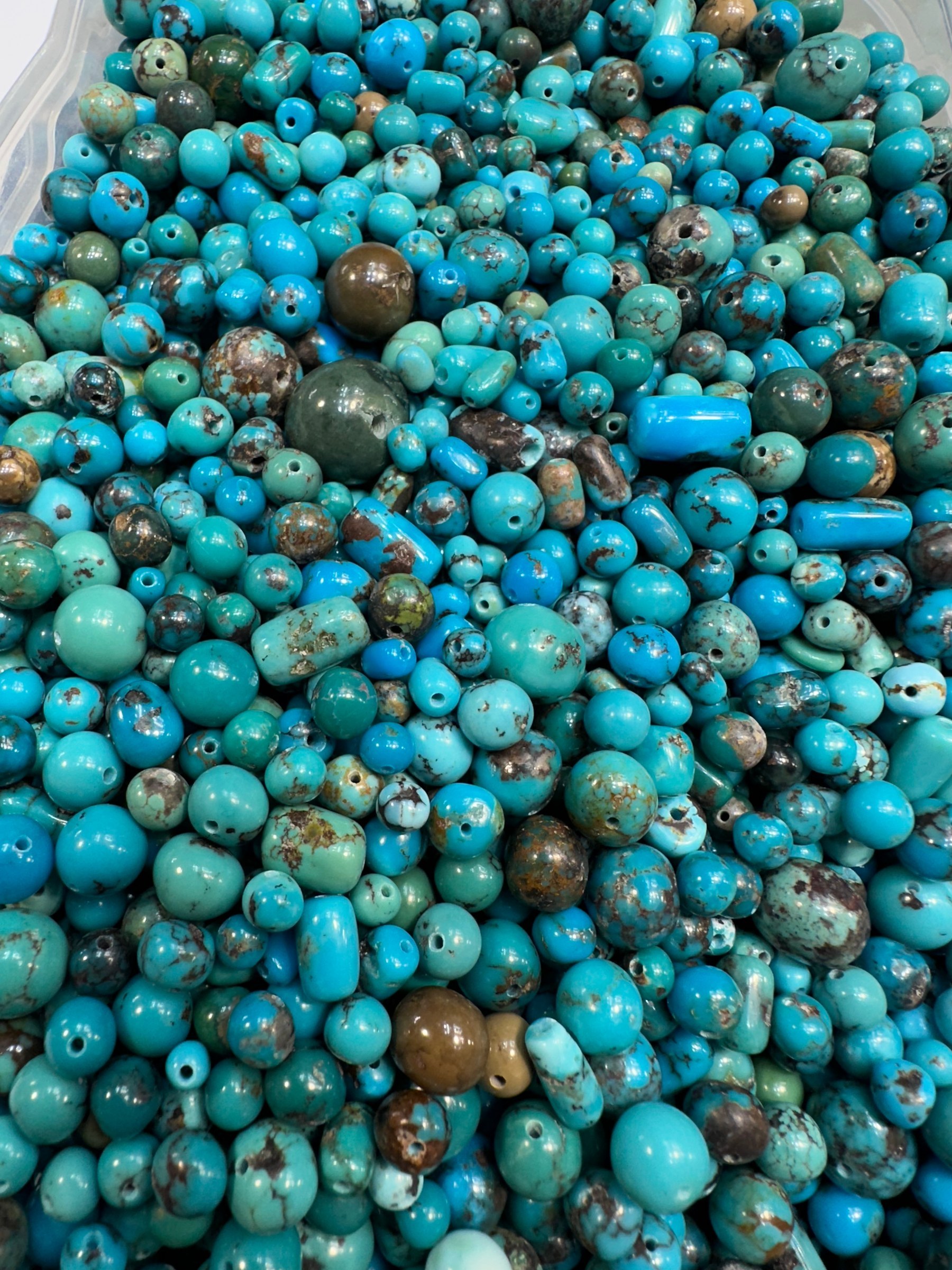 Close view of round drilled turquoise beads in blue with brown and green matrix.