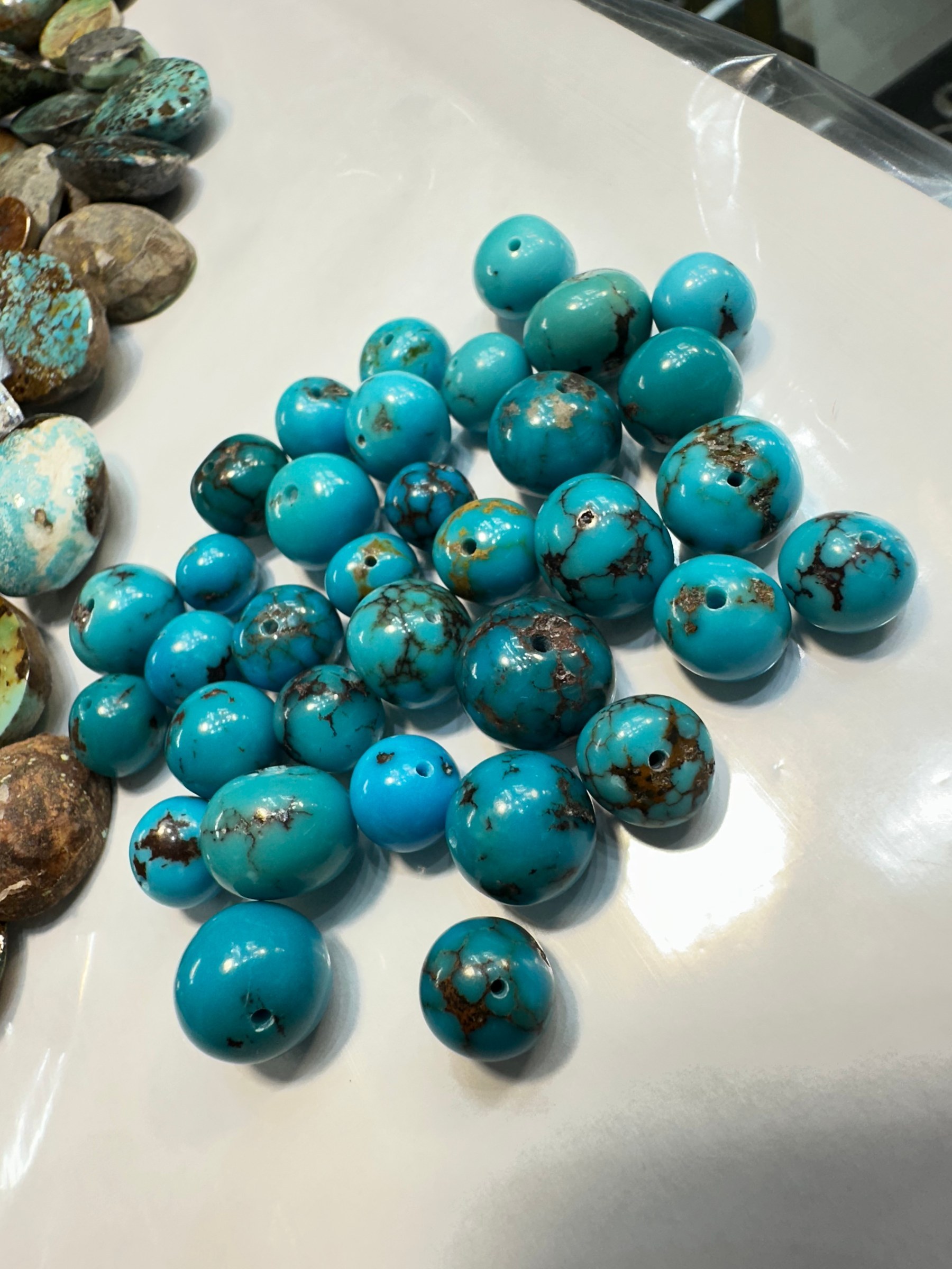 A small group of round polished turquoise cabochons in blue with brown matrix on a white surface.
